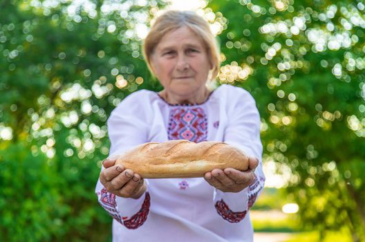 Grandmother with Ukrainian bread in her hands. Selective focus. Food.
