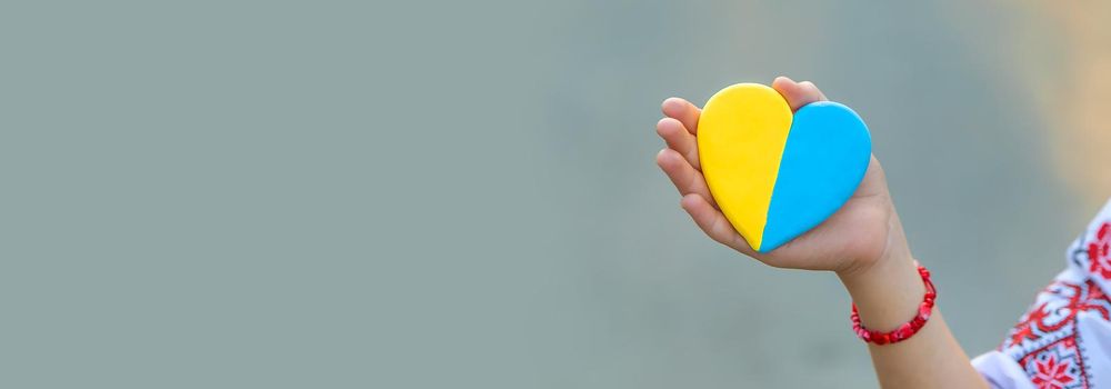 A child holds a heart of the Ukrainian flag. Selective focus. People.