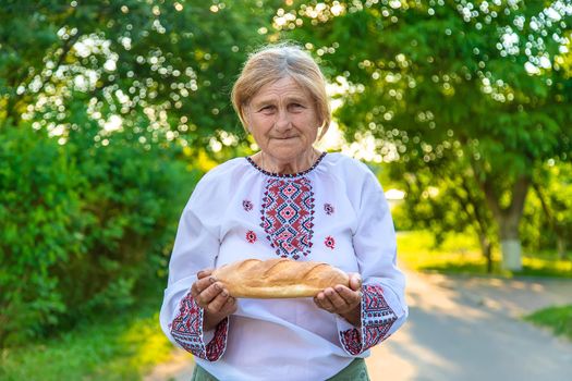 Grandmother with Ukrainian bread in her hands. Selective focus. Food.