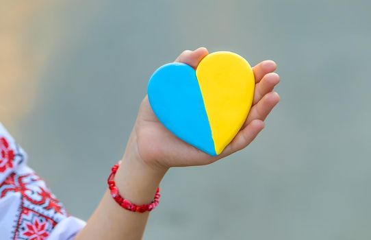 A child holds a heart of the Ukrainian flag. Selective focus. People.