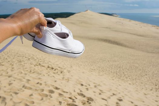 White traveler's sneakers on the background of Pilat dune, the largest sand dune in Europe, France