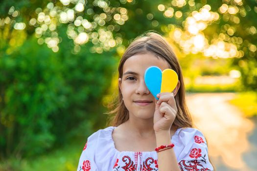 A child holds a heart of the Ukrainian flag. Selective focus. People.