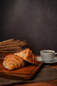 Homemade butter croissant in tray decorated with wheat on wooden table. Levitation, bread bakery products cafe concept.