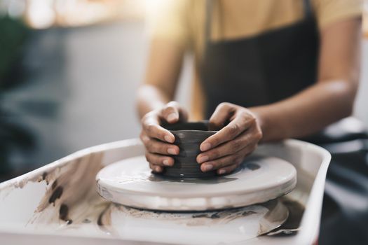 Craftsman hands making pottery bowl. Woman working on potter wheel. Family business shop sculpts pot from clay