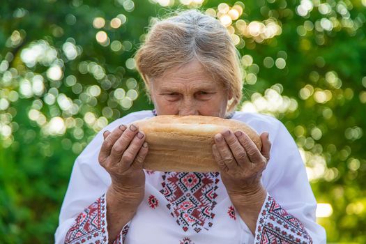 Grandmother with Ukrainian bread in her hands. Selective focus. Food.