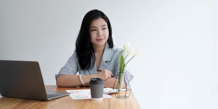 Asian business women sit in the office and drink coffee look laptop computer.