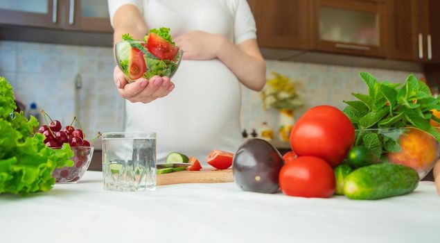 A pregnant woman eats vegetables and fruits. Selective focus. Food.