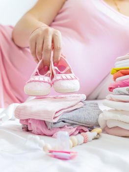 A pregnant woman is folding baby things. Selective focus. people.