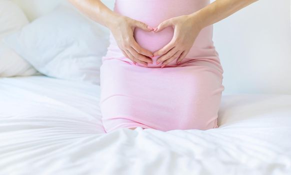 A pregnant woman in bed hugs her stomach. Selective focus. people.