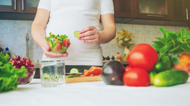 A pregnant woman eats vegetables and fruits. Selective focus. Food.