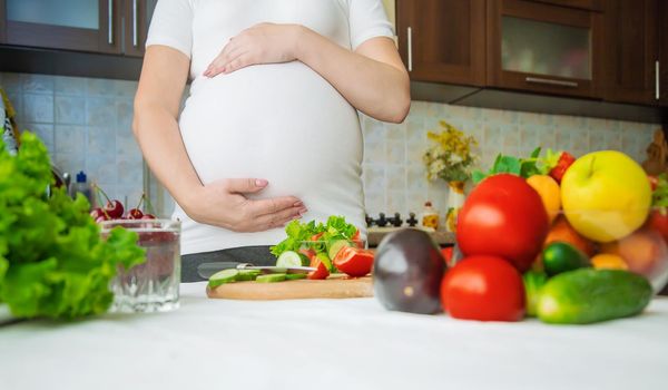 A pregnant woman eats vegetables and fruits. Selective focus. Food.