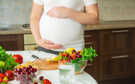 A pregnant woman eats vegetables and fruits. Selective focus. Food.