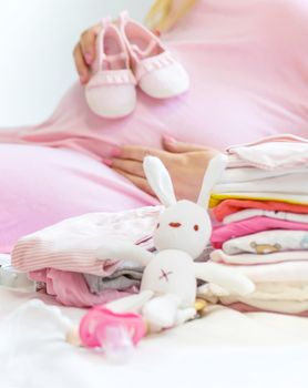 A pregnant woman is folding baby things. Selective focus. people.