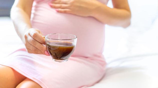 A pregnant woman is drinking coffee. Selective focus. people.