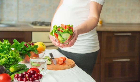 A pregnant woman eats vegetables and fruits. Selective focus. Food.