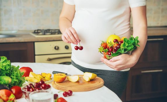 A pregnant woman eats vegetables and fruits. Selective focus. Food.