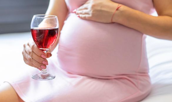 A pregnant woman is drinking wine. Selective focus. people.