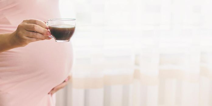 A pregnant woman is drinking coffee. Selective focus. people.