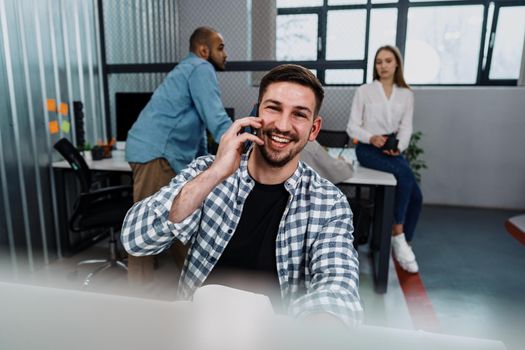 Portrait of young man sitting and working at his desk in the office, close up