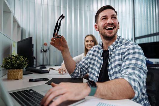 Portrait of young man sitting and working at his desk in the office, close up