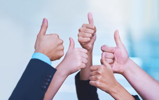 Shot of a group of office workers showing thumbs up together.