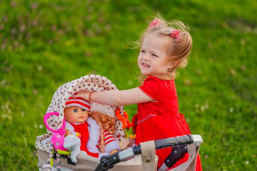 girl plays with her doll who is sitting in a toy stroller