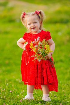 girl in a red dress and with a bouquet of wild flowers on the lawn