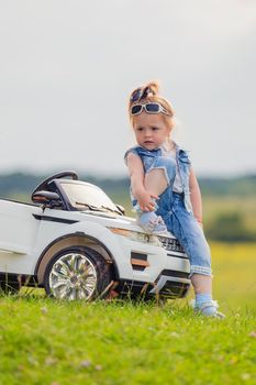 little girl standing near her baby car