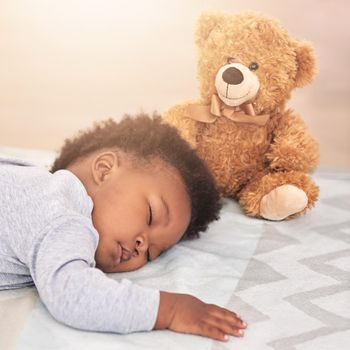 Shot of a little baby boy sleeping on a bed with a teddy bear.
