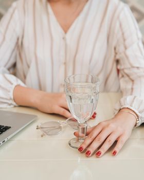 Close Up of Unrecognisable Woman Sitting by Table with Laptop, Glass of Water and Glasses
