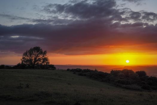 Stunning orange sunset looking out from Butser Hill, the highest point on the chalk ridge of the South Downs, Hampshire, UK