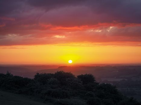 Stunning orange sunset looking out from Butser Hill, the highest point on the chalk ridge of the South Downs, Hampshire, UK