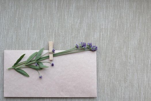 Envelope mockup and dry lavender flowers on canvas background, top view, copy space. Vintage style. A small bouquet of dry lavender on a vintage-style craft envelope. Happy Birthday, Valentine's day, wedding, Mother's Day greeting card concept.