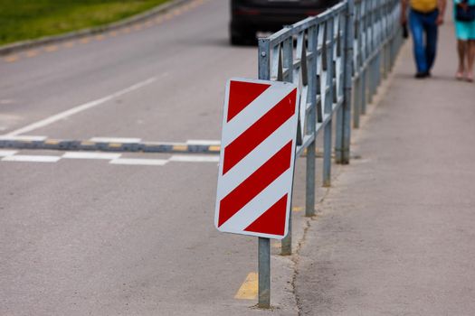 warning red and white diagonal striped vertical marking 8.22.2 sign at the end of road fence, separating road and