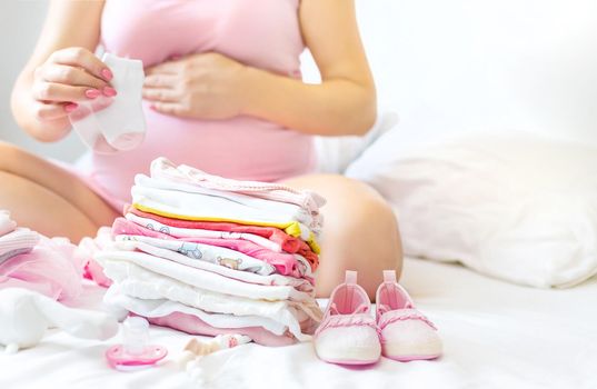 A pregnant woman is folding baby things. Selective focus. people.
