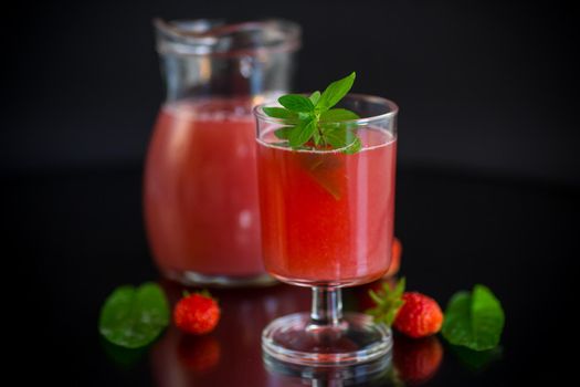 Cold summer strawberry kvass with mint in a glass isolated on black background