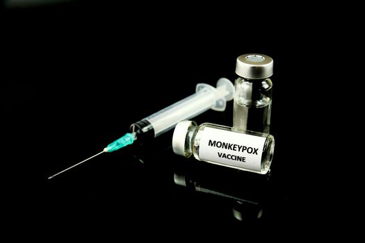 Close up picture of syringe and vials filled with Monkeypox vaccine on black background.