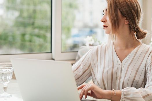 Young Business Woman Looking Away Through Window While Working on Laptop