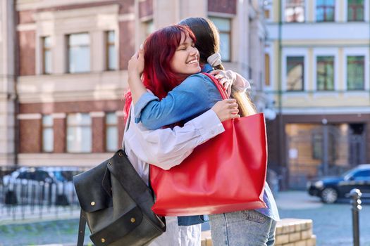 Meeting of two teenage girls friends, outdoor on city street. Happy joyful fashionable females embrace greeting. Joy happiness together, friendship communication lifestyle, youth concept