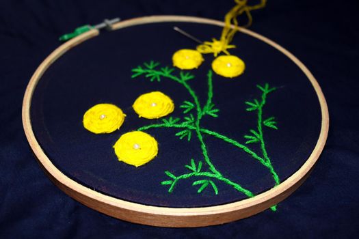 yellow and green colored woolen handicraft sewing embroidery work with circle frame on cloth