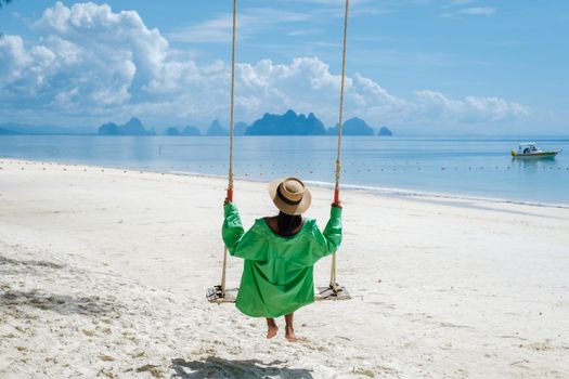 woman on the beach of the tropical Island Naka Island near Phuket Thailand, the woman at a swing on the beach. Naka Island Phuket Thailand