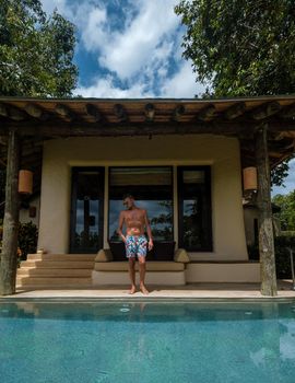 European man at infinity pool in Thailand looking out over the ocean, luxury vacation in Thailand, private pool villa. High quality photo