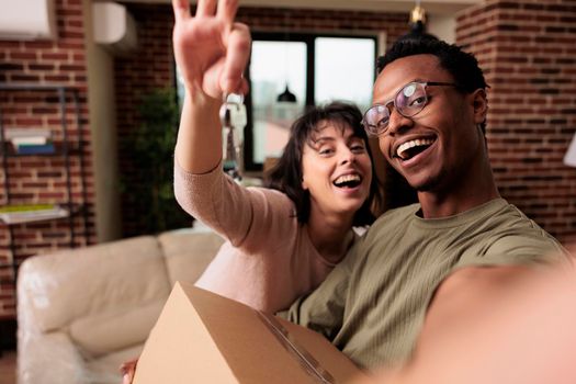 POV of happy homeowners holding house keys of rented flat, moving in new household property together to start family. Enjoying relocation and life event for new beginnings, real estate.