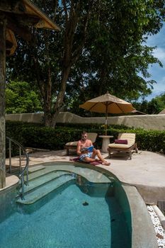 European man at infinity pool in Thailand looking out over the ocean, luxury vacation in Thailand, private pool villa. High quality photo