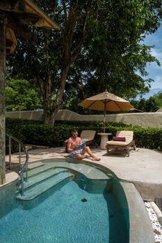 European man at infinity pool in Thailand looking out over the ocean, luxury vacation in Thailand, private pool villa. High quality photo