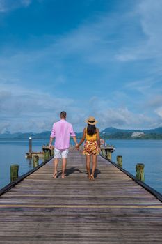couple men and woman on a tropical island with wooden pier jetty in Thailand Phuket Naka Island