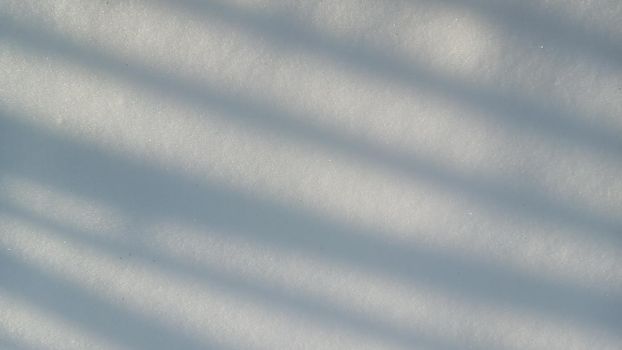 Background with natural snow texture, close-up from above. Shadow in the form of straight lines on a snowy surface, abstract background.