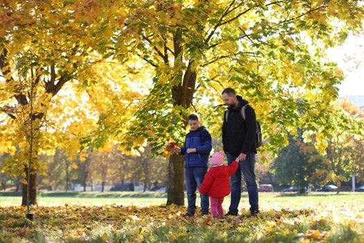 Happy father playing with his children outside in the park.