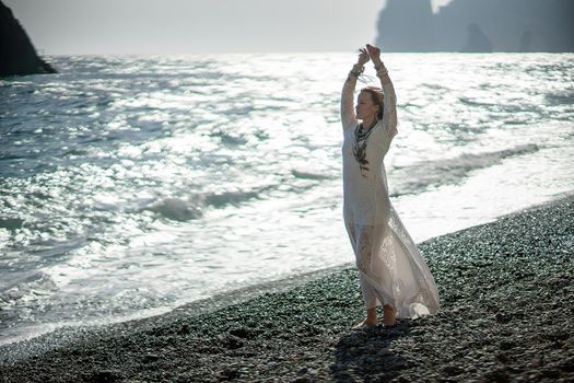 Middle aged woman looks good with blond hair, boho style in white long dress on the beach decorations on her neck and arms