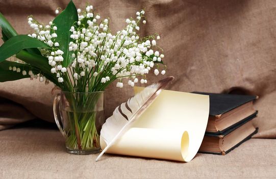 Still life with open book and quill pen near posy of white lilies